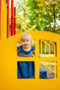 Child playing on outdoor playground. Little baby girl plays on school or kindergarten yard. Active kid on colorful swing Royalty Free Stock Photo