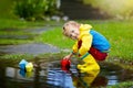 Child with paper boat in puddle. Kids by rain. Royalty Free Stock Photo