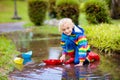 Child with paper boat in puddle. Kids by rain Royalty Free Stock Photo