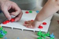 Child playing with pegboard mushroom nail mosaic