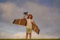 Child playing. Child pilot aviator with with paper wings or toy airplane dreams of traveling in summer in nature. Royalty Free Stock Photo