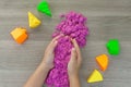 a child is playing in pink kinetic sand