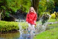 Child playing in puddle. Kids jump in autumn rain