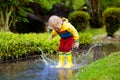 Child playing in puddle. Kids jump in autumn rain