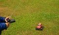 A child is playing with a radio-controlled typewriter. A little racing driver. Radio-controlled red car on green grass Royalty Free Stock Photo