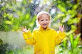 Child playing in the rain. Kid with umbrella