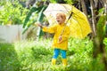 Child playing in the rain. Kid with umbrella