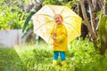 Child playing in the rain. Kid with umbrella