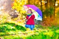 Child playing in the rain with umbrella in autumn park Royalty Free Stock Photo