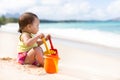 Child playing on sandy beach with a bucket and shovel