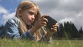 Child Playing Smartphone Outdoor in Park, Kid use Tablet on Meadow Girl in Grass Royalty Free Stock Photo