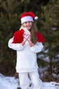 Child playing in snow on Christmas vacation. Winter outdoor fun. Kids play in snowy park on Xmas eve. Little girl in Santa hat, Royalty Free Stock Photo