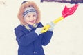 A child is playing with snow with a shovel in the winter. Royalty Free Stock Photo