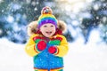 Child playing with snow in winter. Kids outdoors.