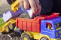 The child is playing in the street with sand; he loads the earth in an dump truck toy Royalty Free Stock Photo