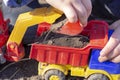 The child is playing in the street with sand; he loads the earth in an dump truck toy Royalty Free Stock Photo