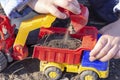 The child is playing in the street with sand; he loads the earth in an dump truck toy Royalty Free Stock Photo