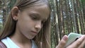 Child playing tablet outdoor in camping, kid use smartphone, lost girl in forest