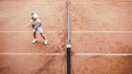 Child playing tennis on outdoor clay court. Top view of little tennis player on open tennis court. Full length shot of sporty Royalty Free Stock Photo