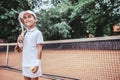 Child playing tennis on outdoor court. Little girl with tennis racket and ball in sport club