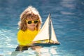 Child playing with a toy boat. Little kid boy sailing toy ship on sea water. Summer vacation with kids. Kid dreaming Royalty Free Stock Photo