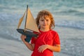 Child playing with a toy boat. Little kid boy sailing toy ship on sea water. Summer vacation with kids. Kid dreaming Royalty Free Stock Photo