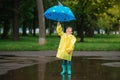 Child playing with toy boat in puddle. Kid play outdoor by rain. Fall rainy weather outdoors activity for young children. Kid Royalty Free Stock Photo