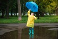 Child playing with toy boat in puddle. Kid play outdoor by rain. Fall rainy weather outdoors activity for young children. Kid Royalty Free Stock Photo