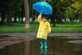 Child playing with toy boat in puddle. Kid play outdoor by rain. Fall rainy weather outdoors activity for young children. Kid Royalty Free Stock Photo