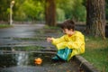 Child playing with toy boat in puddle. Kid play outdoor by rain. Fall rainy weather outdoors activity for young children. Kid Royalty Free Stock Photo