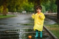 Child playing with toy boat in puddle. Kid play outdoor by rain. Fall rainy weather outdoors activity for young children. Kid Royalty Free Stock Photo