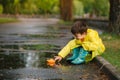 Child playing with toy boat in puddle. Kid play outdoor by rain. Fall rainy weather outdoors activity for young children. Kid Royalty Free Stock Photo