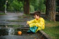 Child playing with toy boat in puddle. Kid play outdoor by rain. Fall rainy weather outdoors activity for young children. Kid Royalty Free Stock Photo