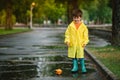 Child playing with toy boat in puddle. Kid play outdoor by rain. Fall rainy weather outdoors activity for young children. Kid Royalty Free Stock Photo