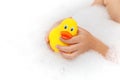 Child playing with toy rubber duck in bath with soap foam. Royalty Free Stock Photo