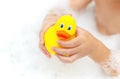 Child playing with toy rubber duck in bath with soap foam. Royalty Free Stock Photo