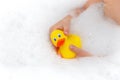 Child playing with toy rubber duck in bath with soap foam. Royalty Free Stock Photo