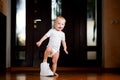 A child playing trying on a big sneaker of a father, standing in the corridor Royalty Free Stock Photo