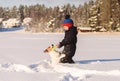 Child playing tug-of-war game with pet dog pulls flying disc in deep snow on winter day Royalty Free Stock Photo