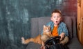 child playing video game with console. funny kid with his friend red pet cat playing at home. School boy is relaxing at Royalty Free Stock Photo