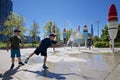 Child playing water from the fountain in the public park in summer