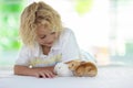 Child playing with white rabbit. Little boy feeding and petting white bunny. Easter celebration. Egg hunt with kid and pet animal Royalty Free Stock Photo