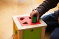 Child playing with wooden bricks in diffrent shapes and colors trying to put them into the proper hole Royalty Free Stock Photo