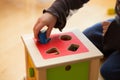 Child playing with wooden bricks in diffrent shapes and colors trying to put them into the proper hole