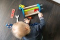 Child playing with wooden toy tool box on the floor Royalty Free Stock Photo