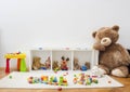 A child playroom with a giant teddy bear and many colorful toys scattered on the floor, at home