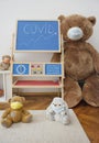 A child playroom with a giant teddy bear wearing medical mask and the growing graph of COVID-2019 cases drawn with chalk on a