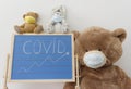 A child playroom with a giant teddy bear wearing medical mask and the growing graph of COVID-2019 cases drawn with chalk on a