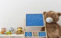 A child playroom with a giant teddy bear wearing medical mask and the growing graph of COVID-2019 cases drawn with chalk on a