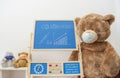 A child playroom or kindergarten with a giant teddy bear wearing medical mask and the growing graph of COVID-2019 cases drawn with